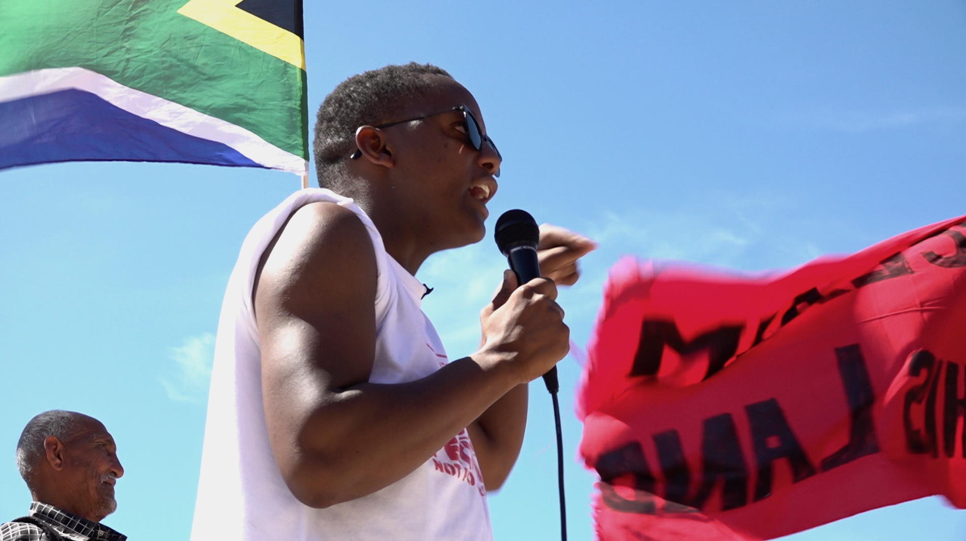 Activist Nkosikhona Swartbooi addresses the crowd at the Occupy Rondebosch Golf Course action
